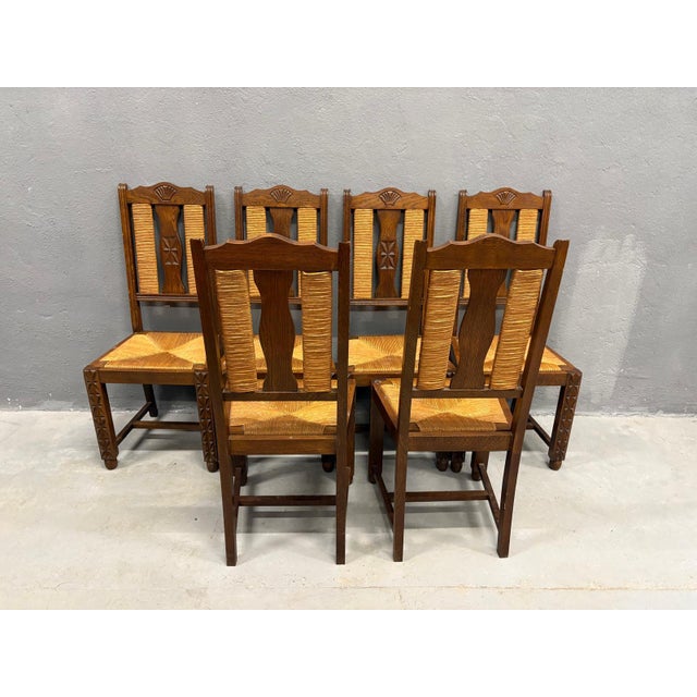 A sculptural set of 6 Brutalist dining chairs from 1950s France, defined by raw ash wood construction and handwoven straw...