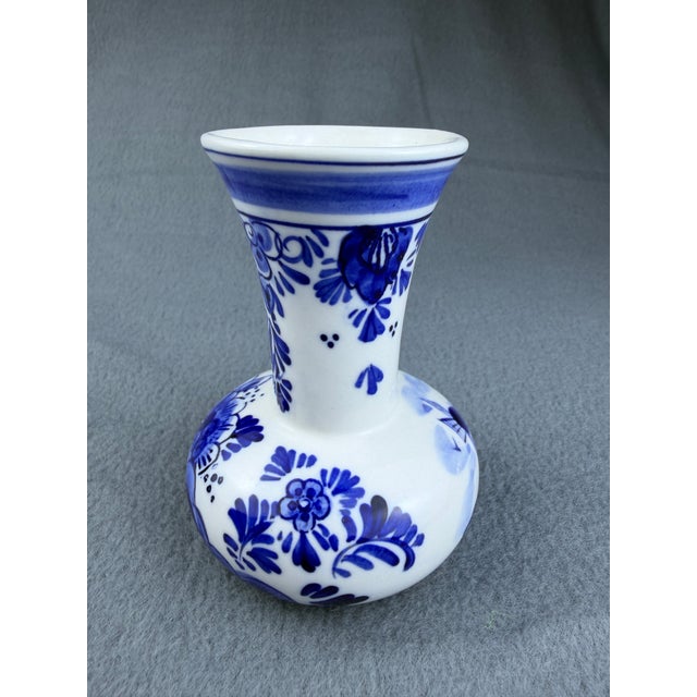 A stunning vintage Delft Blue bud vase, hand-painted in the classic Dutch tradition. The bulbous body features a windmill...