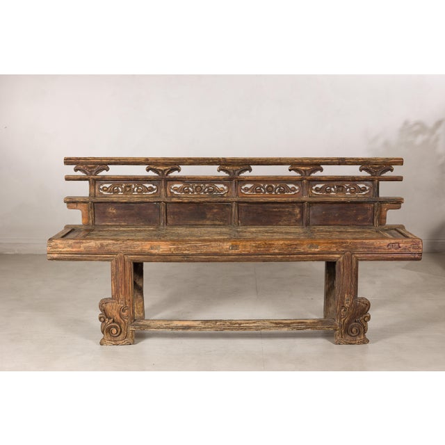 This antique Chinese wooden bench features a richly weathered surface and sculptural silhouette that give it a strong...