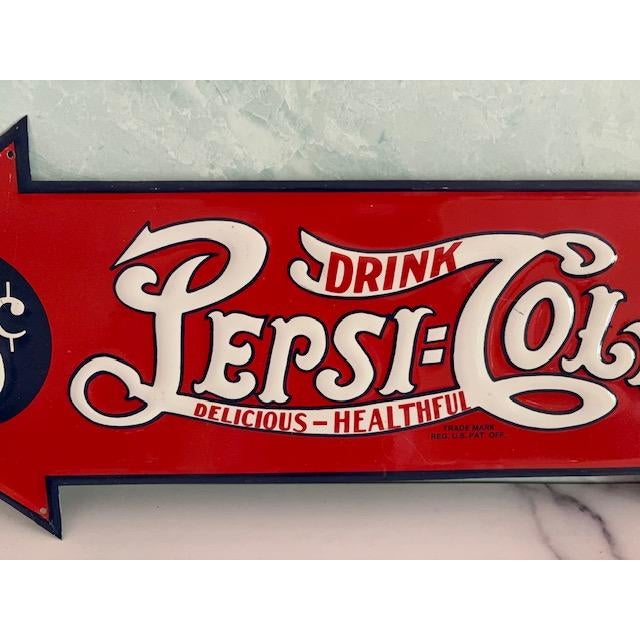 Vintage 1980s reproduction metal sign - Pepsi-Cola. Red, white and blue sign is in the shape of an arrow. Fun to display...