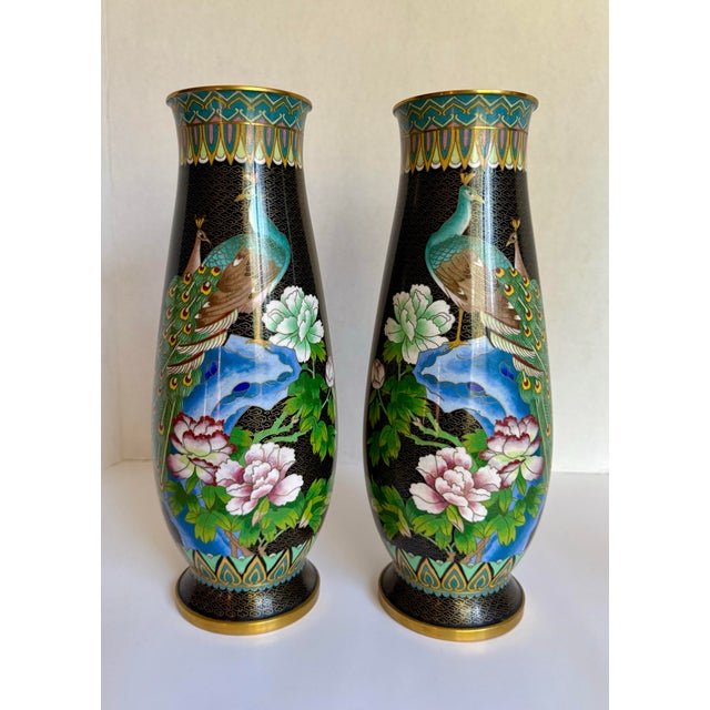 Here is a beautiful pair of vintage Asian cloisonné vases depicting fully plumed peacocks surrounded by a river and pink...