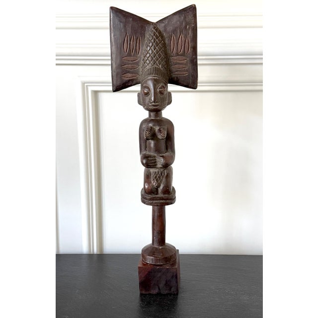 An expressively carved African wood female kneeling figure on staff with a display wood stand circa mid 20th century. The...