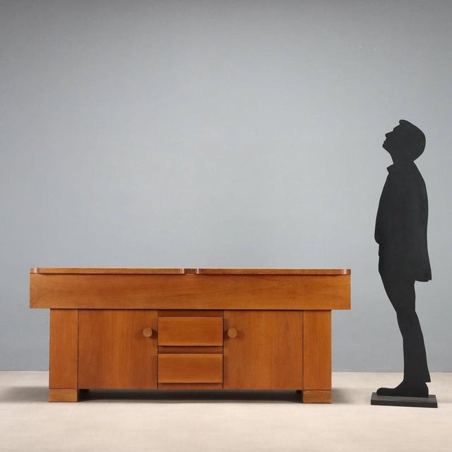 Sideboard with hinged doors and open drawers, designed by Michelucci in 1964, made of walnut veneer. This piece is...