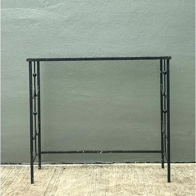 This vintage wrought iron console table balances architectural restraint with graceful, hand-forged detail. A slender...