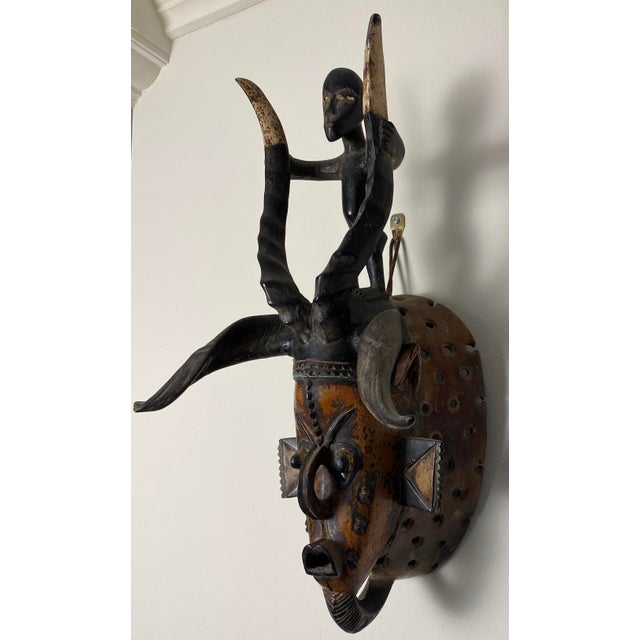 Guro Style African Carved Wood Horned Antelope Mask with Figure, Côte d’Ivoire Striking Guro-style African carved wood...