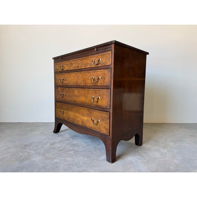 Charming and classically detailed, this 1970s vintage George III-style bachelor’s chest offers timeless English...
