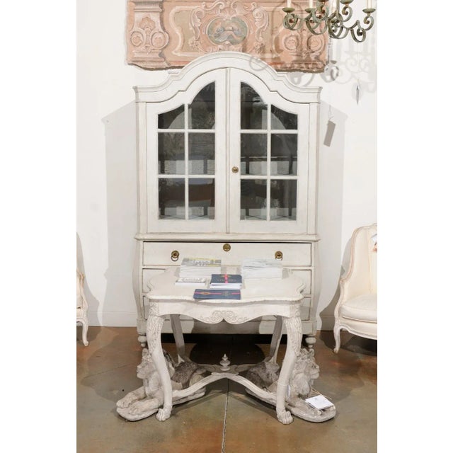 A Swedish painted center table from the mid-19th century, with carved motifs and cross stretcher. Created in Sweden during...