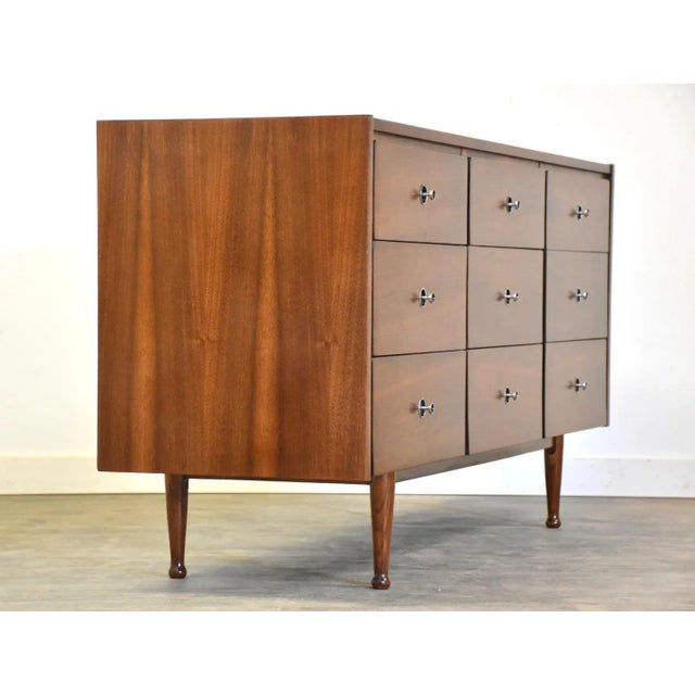 A mid century modern walnut nine drawer dresser by Mainline by Hooker with black and aluminum knobs. Professionally...