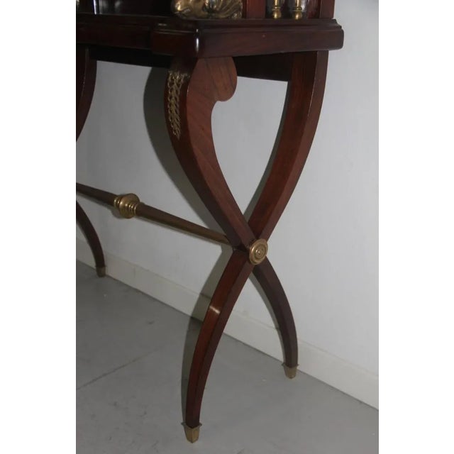 This rosewood showcase from the 1950s has a very special cross-legged base and features brass parts.