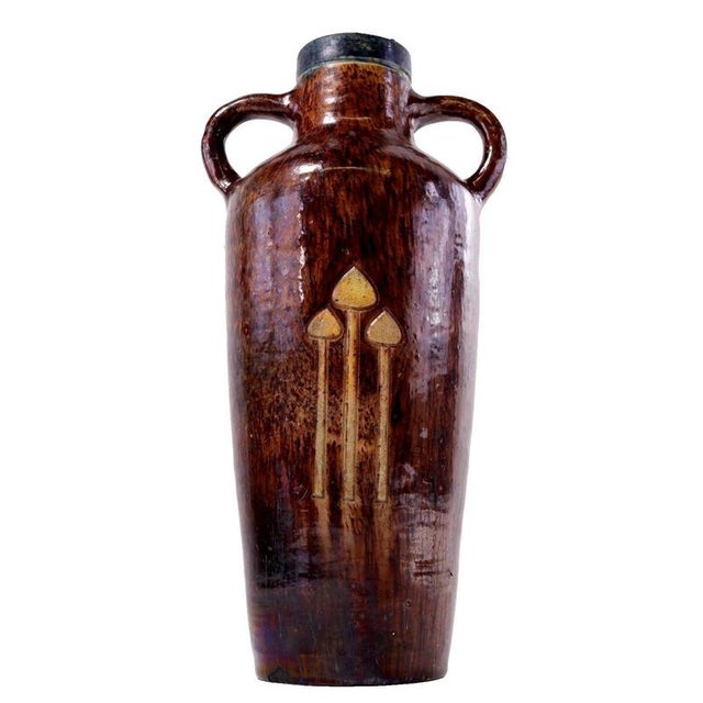 Three stylised toadstool motifs rise in shallow relief across the front of this earthenware vase, each slender stalk...