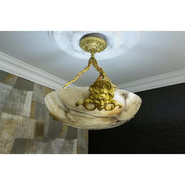 Early 20th-century french alabaster bowl chandelier with sculptural bronze details and classical proportions. elegant...