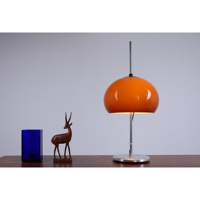 Original 1970s Space Age table lamp with a slender chrome stem and a domed dark amber plastic shade. When illuminated, the...