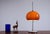 Original 1970s Space Age table lamp with a slender chrome stem and a domed dark amber plastic shade. When illuminated, the...