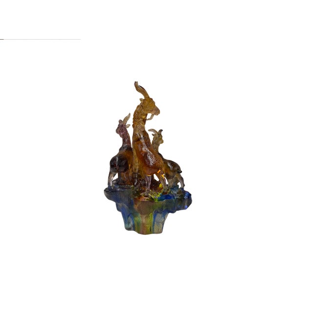 This exquisite crystal sculpture captures a dynamic mountain scene, featuring a small herd of ibex or wild goats poised...
