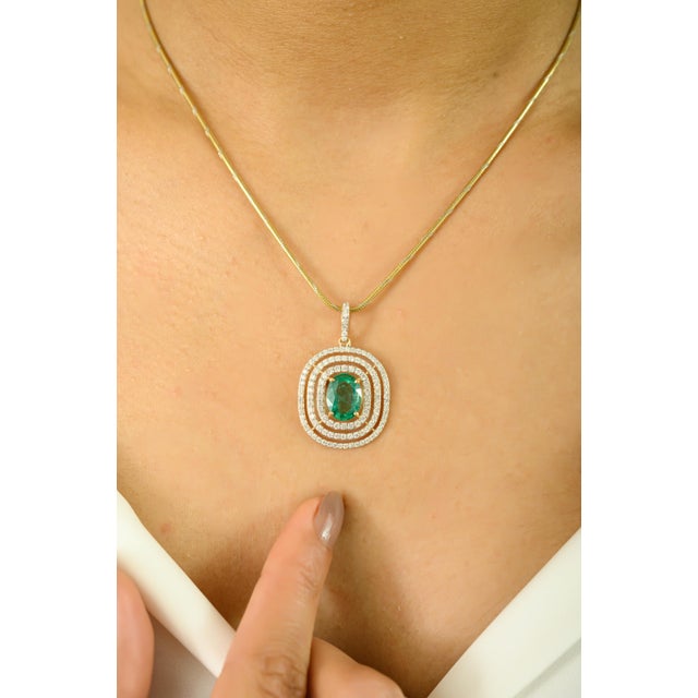 Make a striking impression with this stunning pendant featuring a captivating 1.87 carat oval-cut emerald at its center....