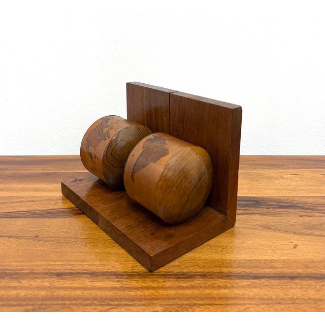 A distinctive pair of vintage wooden bookends featuring rounded sculptural forms with inlaid world map motifs. Crafted...