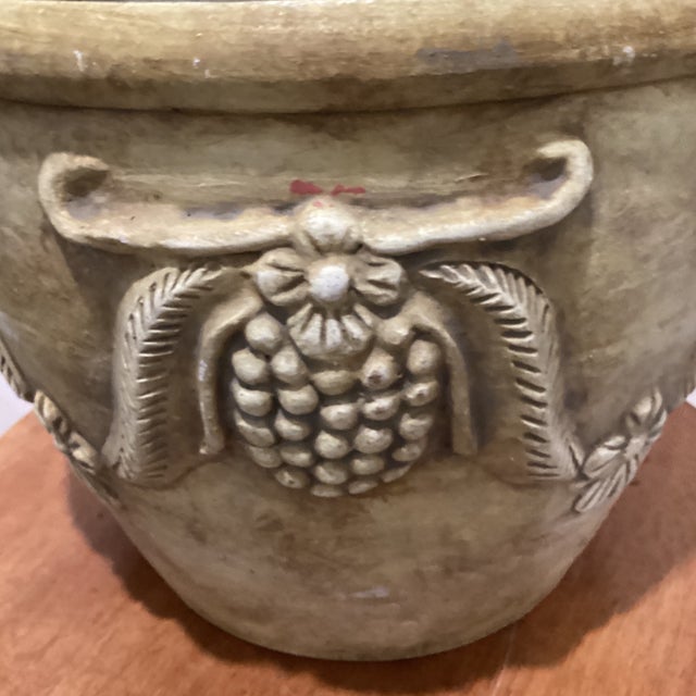 The large aged finish planter in Roseville style features a molded grape and leaf relief design, adding a touch of...