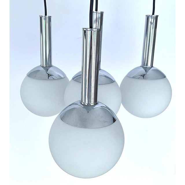Vintage mid century pendant lamp featuring a cascade arrangement of four opaline globe glass shades with chrome caps and...