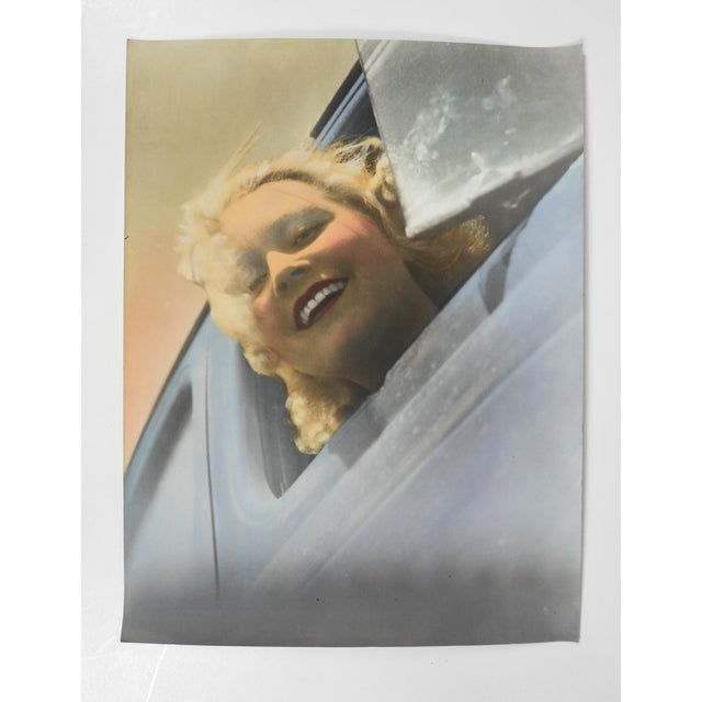 Early 20th century colortone advertising photograph of a smiling blonde woman in a blue car. Unsigned. Unframed, edge and...