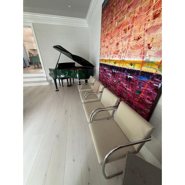 BRNO style Tubular Dining Chairs Four identical cantilever-style chairs with chrome tubular frames and ivory upholstery....