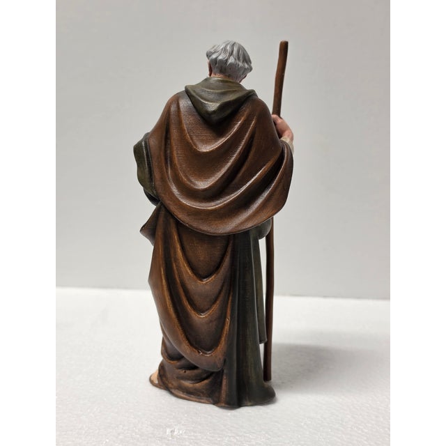 This Italian Baroque style shepherd figurine presents an elderly male figure standing in a humble posture, leaning...