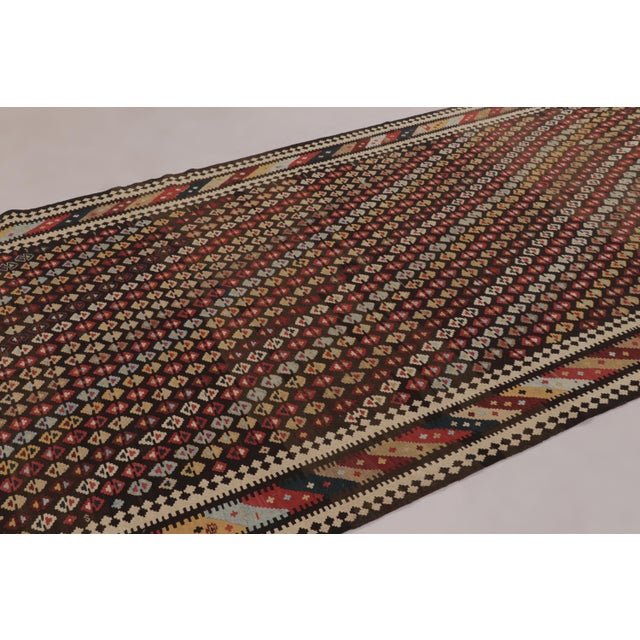 Made with handwoven wool circa 1950-1960, this 6x12 vintage flat-weave Kilim is a particularly complex and sought-after...