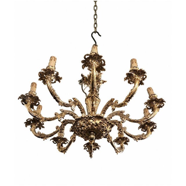 An elegant six-light chandelier crafted from finely chiseled and gilded bronze, featuring a rich decoration of scrolls,...