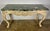 French carved Louis XV style console in a distressed painted finish. The marble top is 2" thick in a soft green...