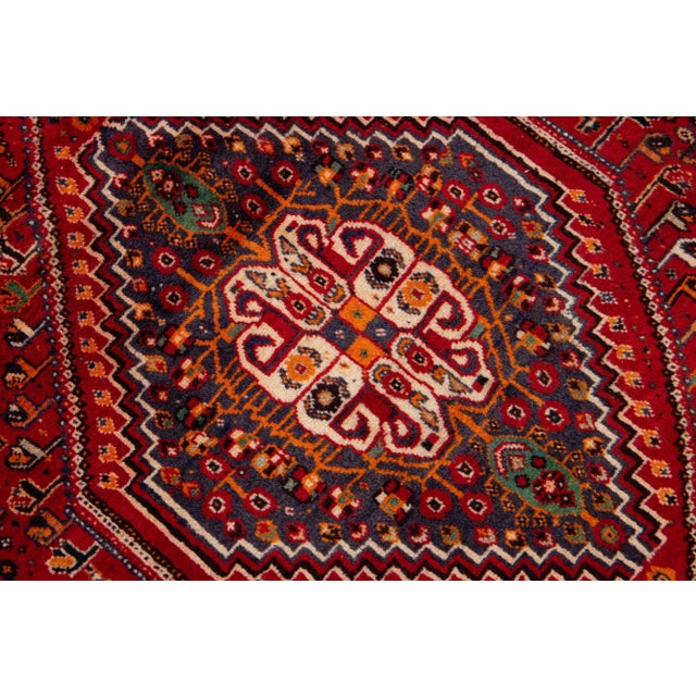Beautiful vintage Persian Shiraz hand-knotted wool rug with a red color field. This piece has multicolor accents in an...