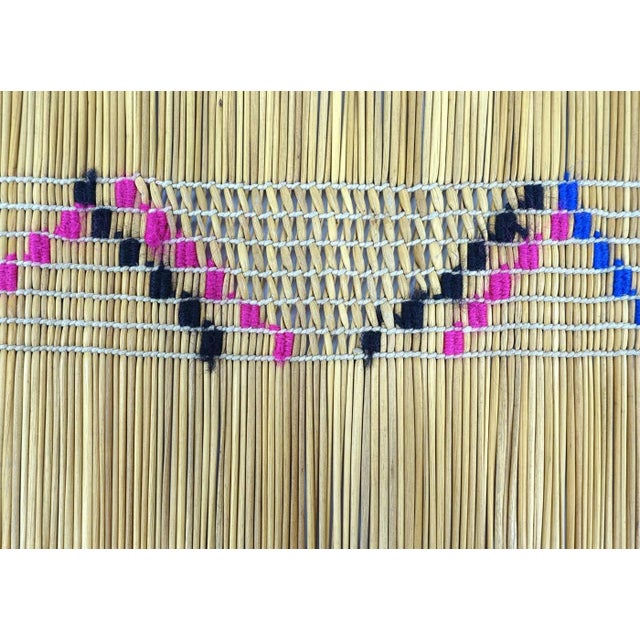 A fine and well-used handwoven square mat made out of straws and decorated with embroidered motifs and openwork patterns....