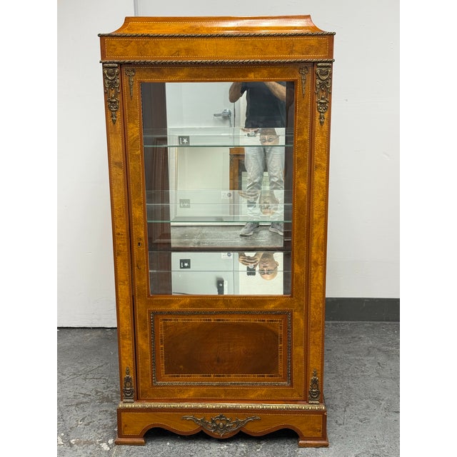 Design Plus Gallery presents a Vintage Louis XVI Style Marquetry Vitrine Display Cabinet. The tall cabinet showcases...