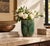 A small, thick-walled pot in deep green glaze, crackled all over like fine veining, with amber drips where the glaze ran...