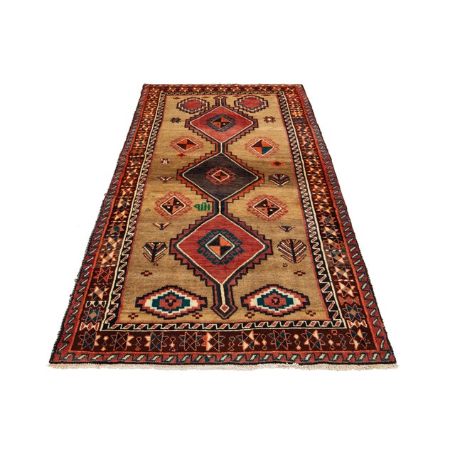 This Persian Shiraz hand-knotted wool rug back from the 1940s has a brown field with a multicolor geometric design. This...