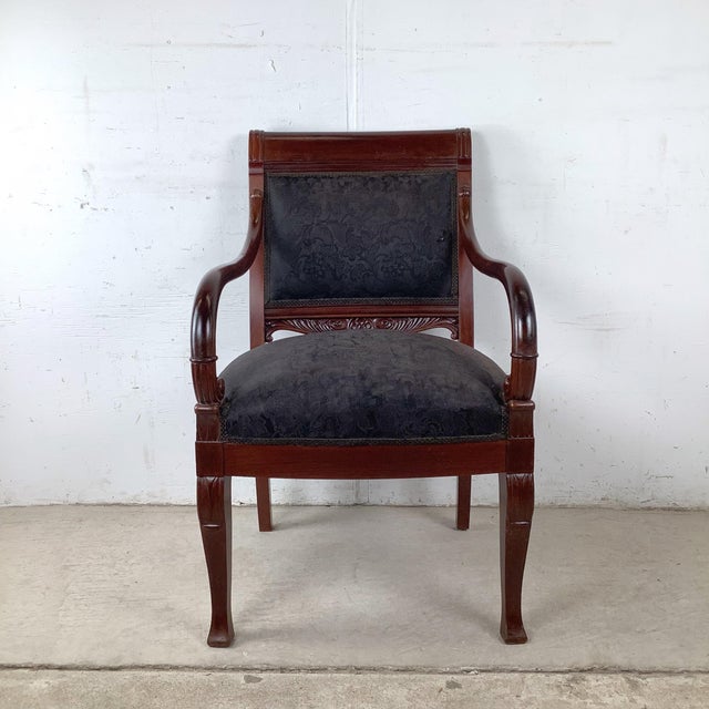 Commanding and deeply elegant, this antique Empire style armchair is a statement piece for the ages. The rich dark...
