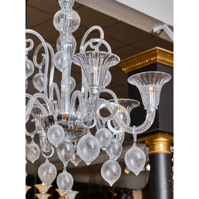 Chandelier made of Murano glass in the cristallo pura color. This piece has six arms from which hang drops of blown glass....