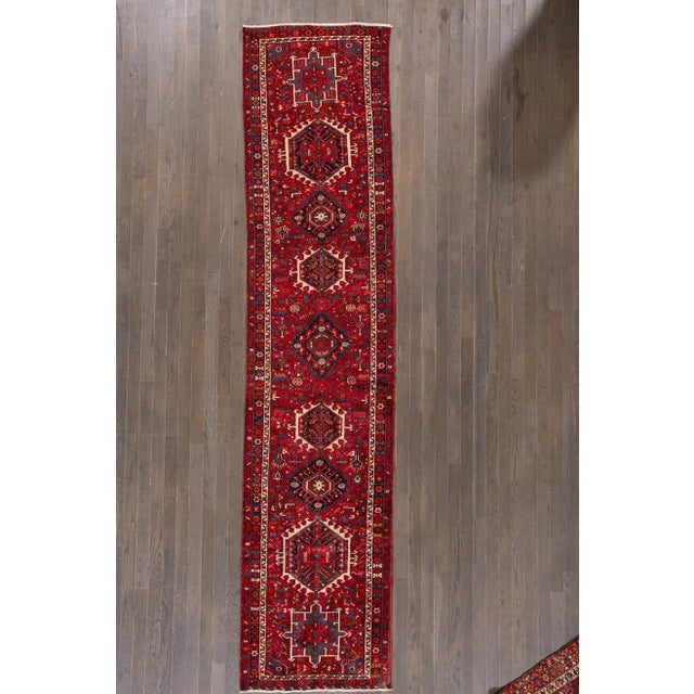 Beautiful vintage Persian Heriz hand-knotted wool runner with a ruby-red field. This rug has a multi-color accent in an...