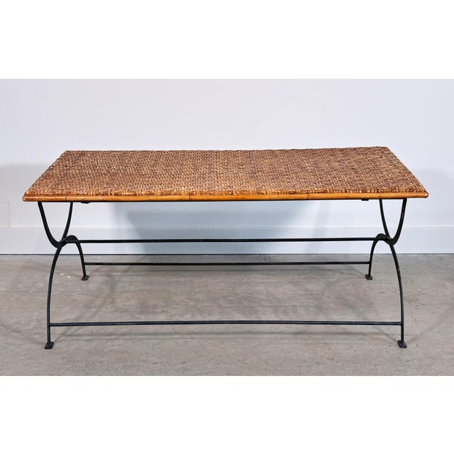 This folding coffee table pairs a herringbone-woven rattan top with a scrolled iron base, a combination that works equally...