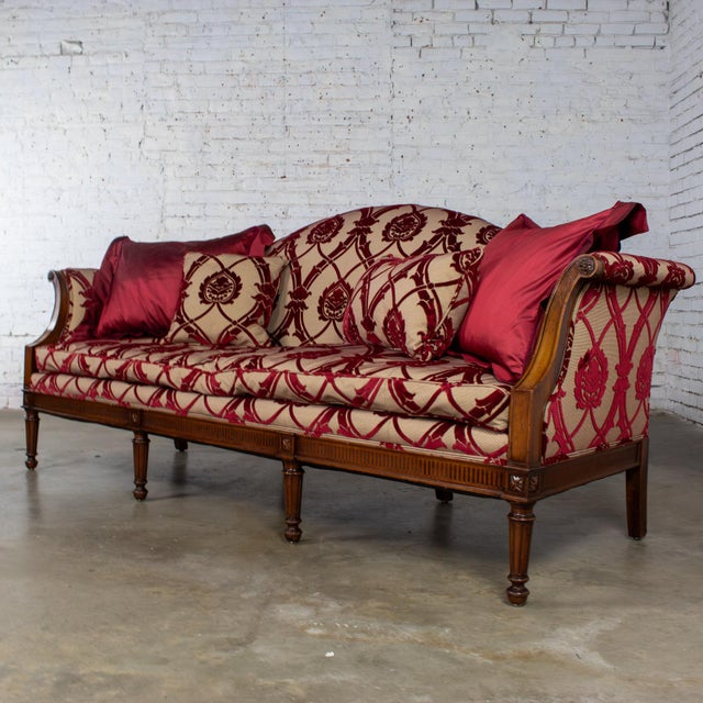 Gorgeous vintage French Louis XVI Directoire style camel back sofa composed of a walnut frame and upholstered in a red and...