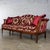 Gorgeous vintage French Louis XVI Directoire style camel back sofa composed of a walnut frame and upholstered in a red and...