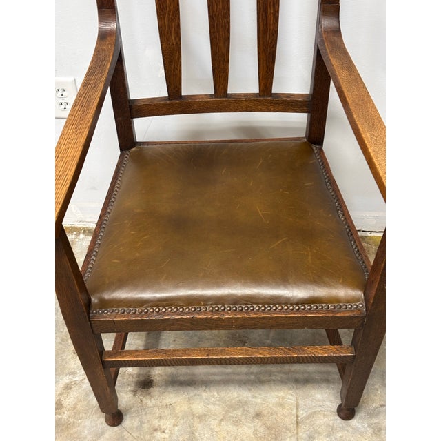 This early 20th century English oak and leather chair reflects the elegance of the Arts and Crafts tradition, where...