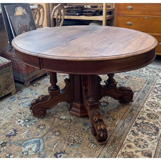 Elegant antique Belgian oval walnut table featuring a richly carved pedestal base with scrolling feet and casters. A...