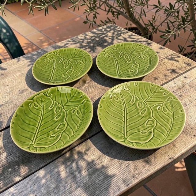 The product is a set of four Monterey Tropical Green Monstera Leaf Dinner Serving Plates. These round ceramic plates...