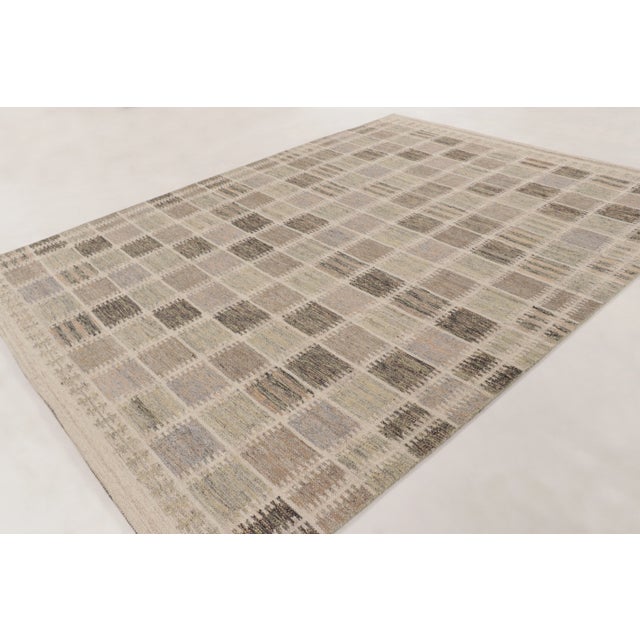 This handwoven wool 9x12 Scandinavian rug features a geometric grid of tonal squares in soft beige, taupe, ivory, and...