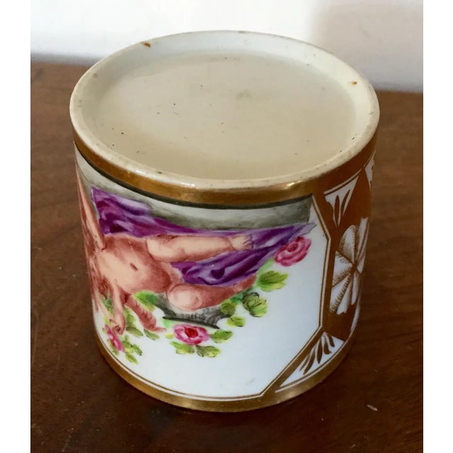 Antique early 19th c. Paris porcelain coffee can. Decorated with a painting of two cherubs enhanced by expert gilding....