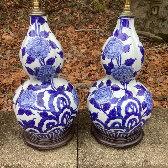 A beautiful pair of vintage double-gourd porcelain lamps featuring hand-painted cobalt blue floral and geometric motifs in...