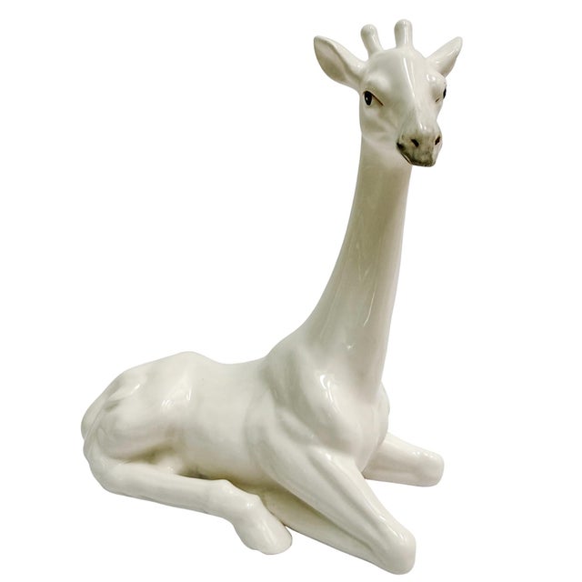 A pair of beautiful and graceful white porcelain giraffes made by Fitz and Floyd in 1971. Both giraffes are in seated...