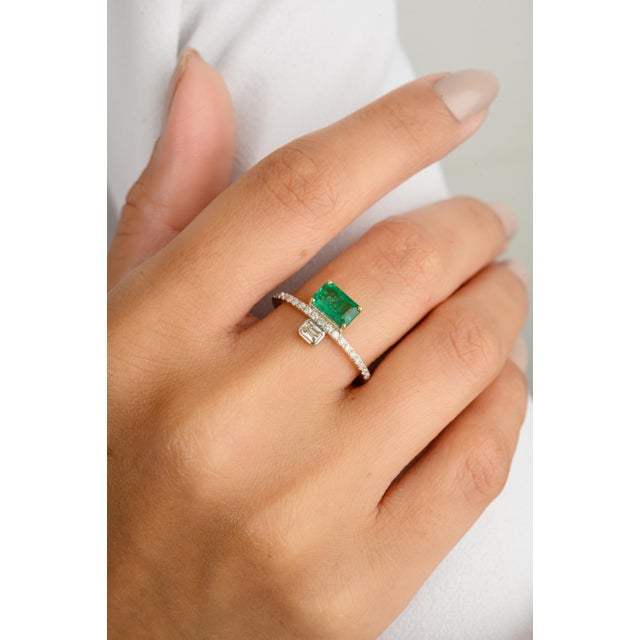 This elegant ring features a modern octagon-cut emerald set east-west, complemented by an octagon-cut diamond. The vibrant...