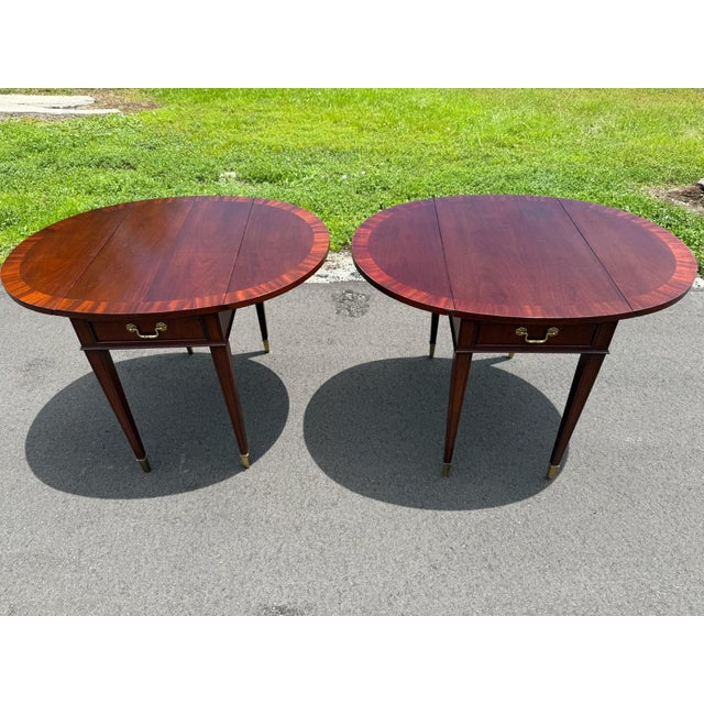 Beautiful matching pair of classic mahogany drop-leaf accent tables featuring rich wood grain, a convenient storage...