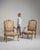 A decorative pair of Louis XV armchairs combining gilded wood frames with tapestry upholstery, reflecting the Rococo...