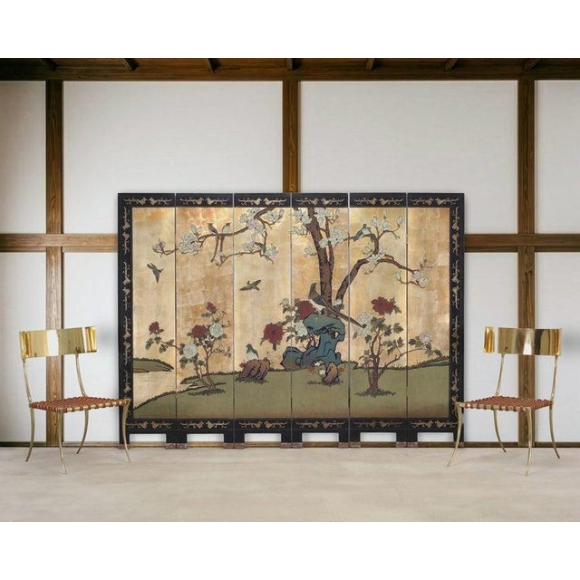 A dramatic six-panel decorative Chinese Export Coromandel screen featuring a warm, luminous reflective gold-leaf ground...